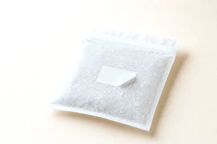 Frost-covered blank plastic freezer bag with condensation droplets and a small blank white label lifting at one corner.