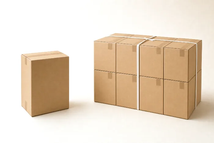 A single blank kraft box facing a ribbon-banded block of eight identical blank boxes stacked two high.